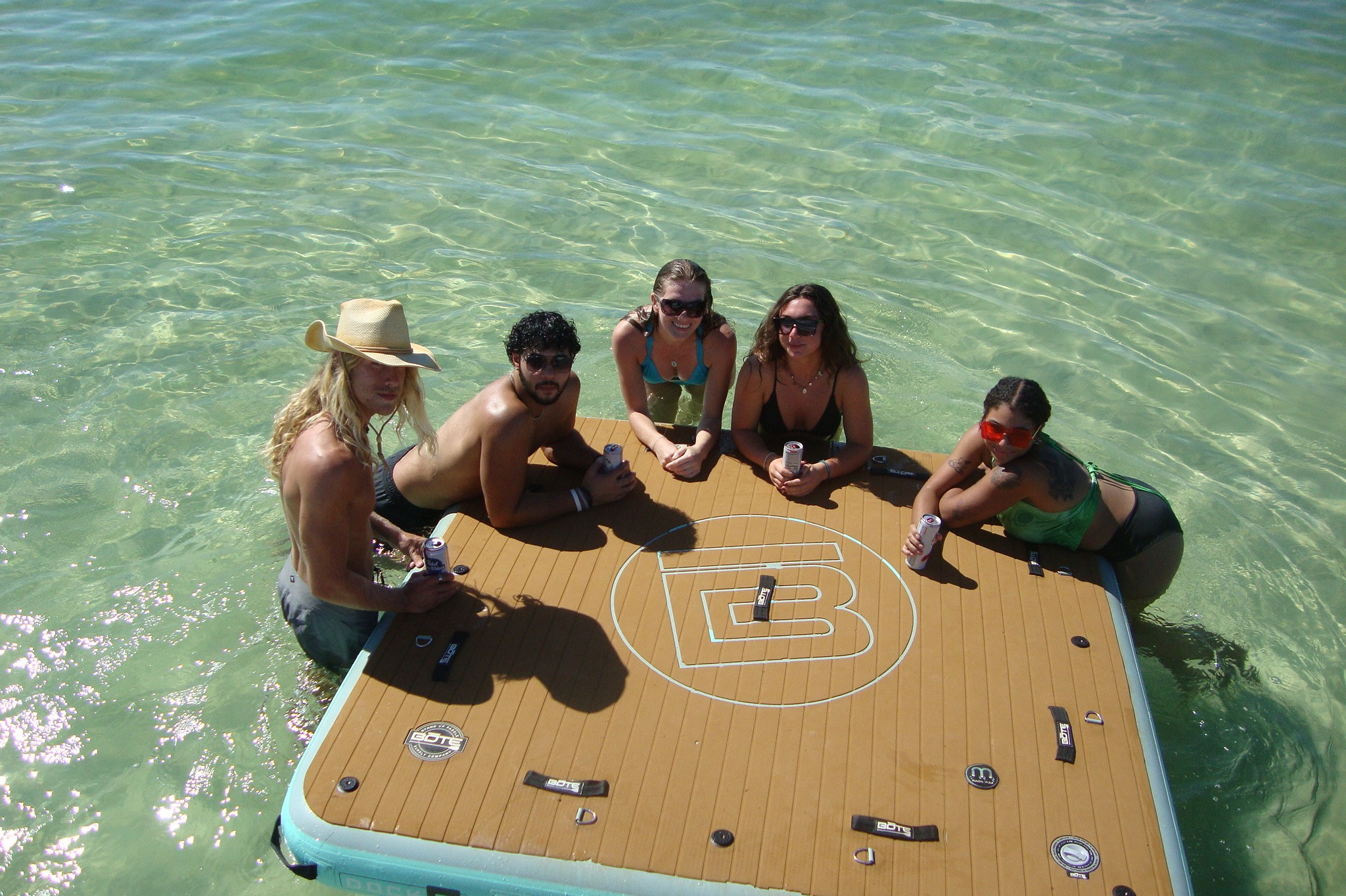 Friends in the shallows at Crab Island gathered around a floating dock with drinks