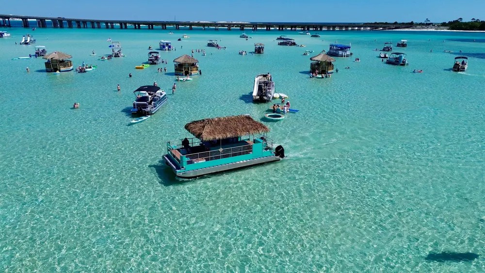 Tiki boats floating over the sandbar with the Destin bridge behind