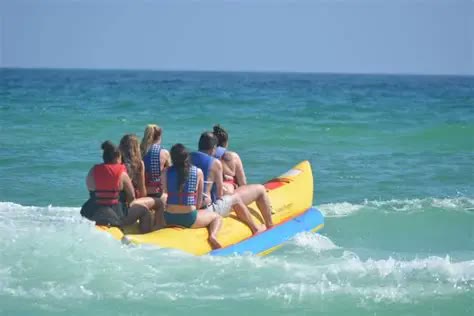 A group riding a yellow banana boat through the surf