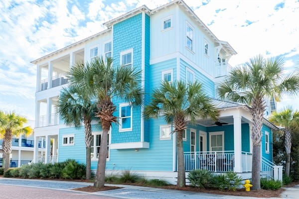 A blue beach house with palm trees on 30A
