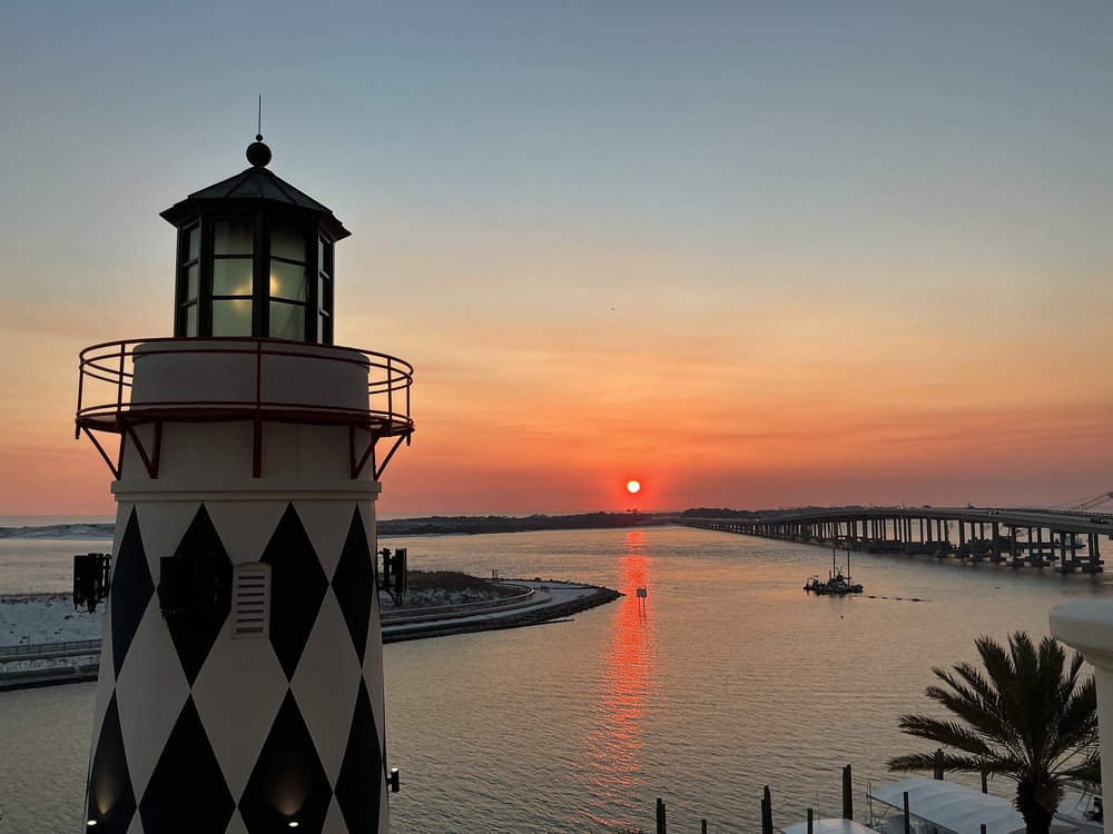 The Destin lighthouse against a sunset over the harbor