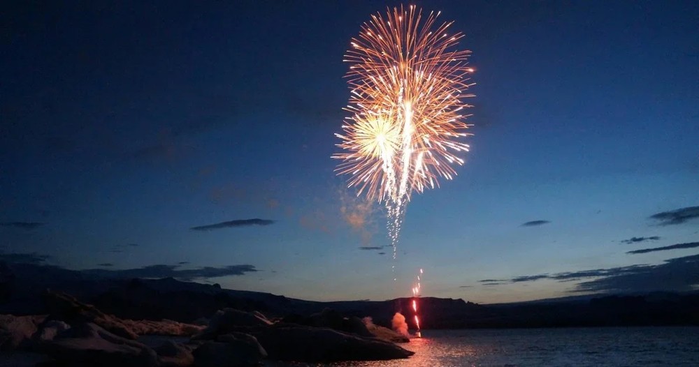 Fireworks bursting over dark water at night