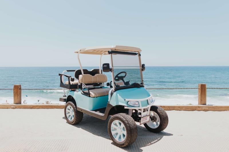 A teal golf cart parked at the beach
