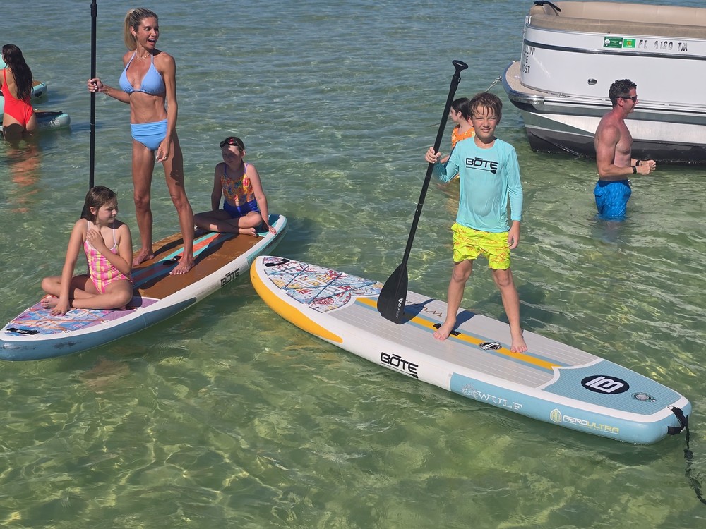 A family paddleboarding in shallow clear water at Crab Island