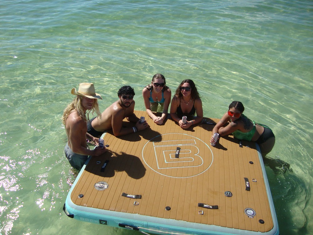Friends in the shallows at Crab Island gathered around a floating dock with drinks