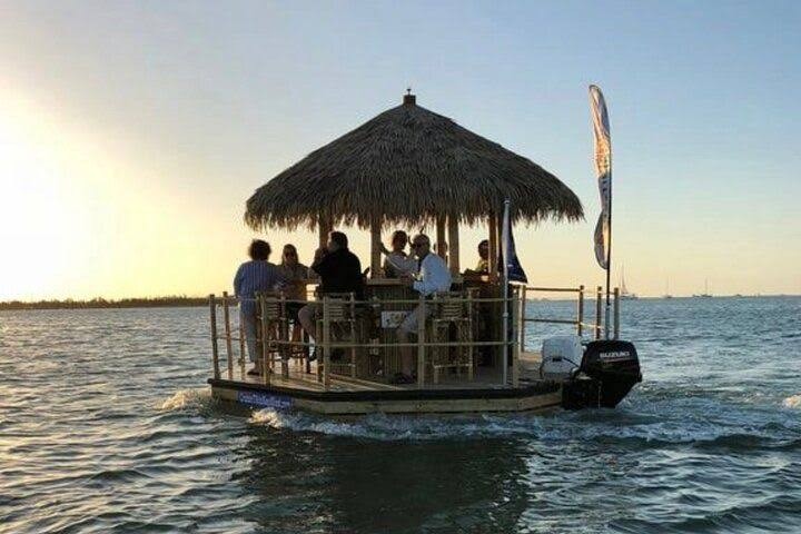 A thatched tiki boat underway at sunset