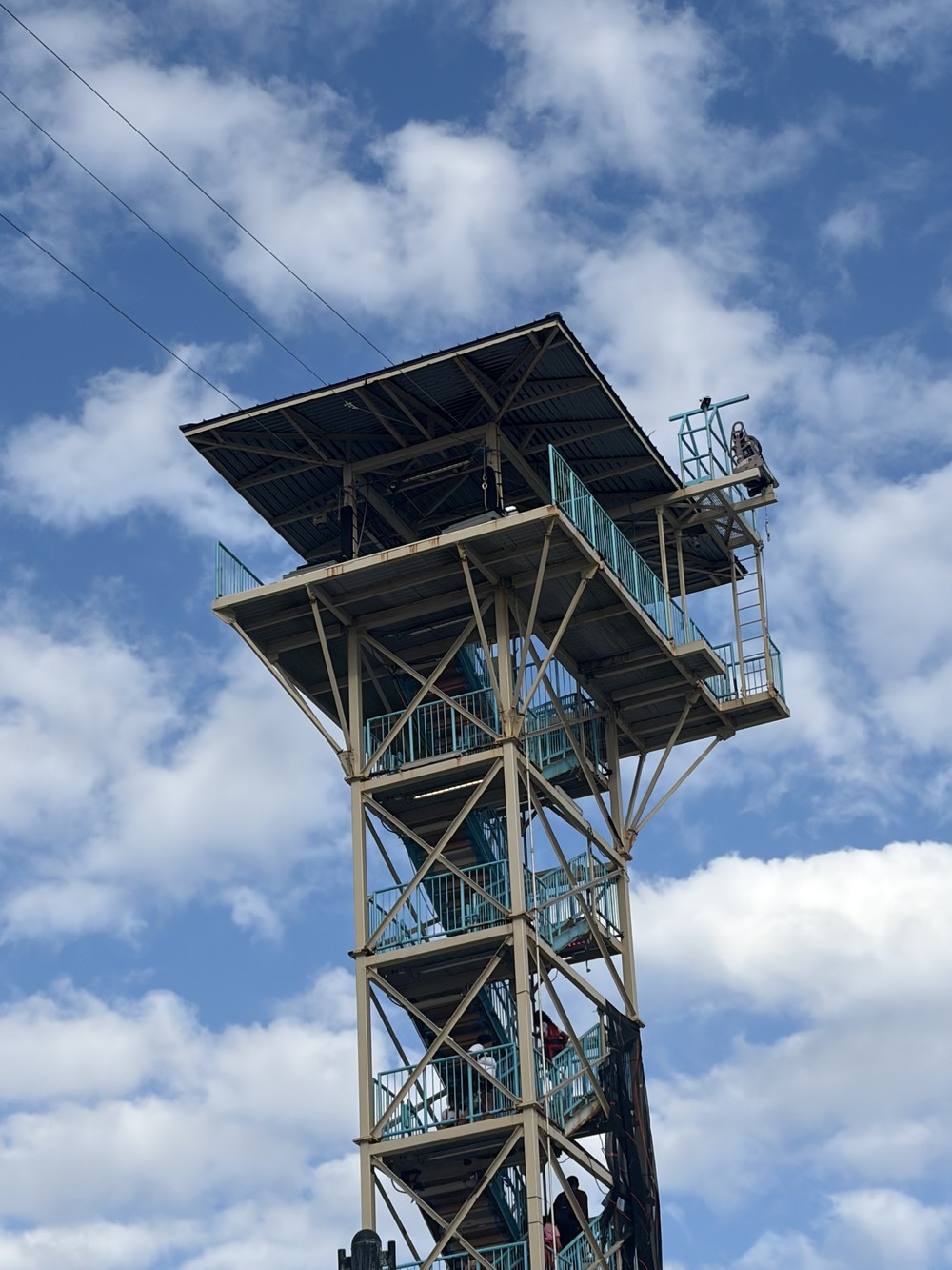 A tall observation tower with teal railings against a blue sky